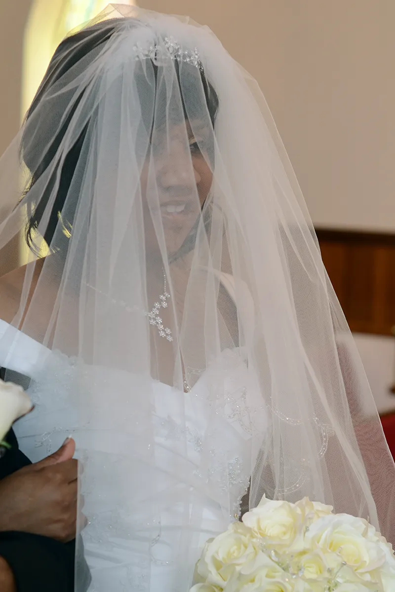 Bride smiling through veil holding white rose bouquet- SJRIMAGES